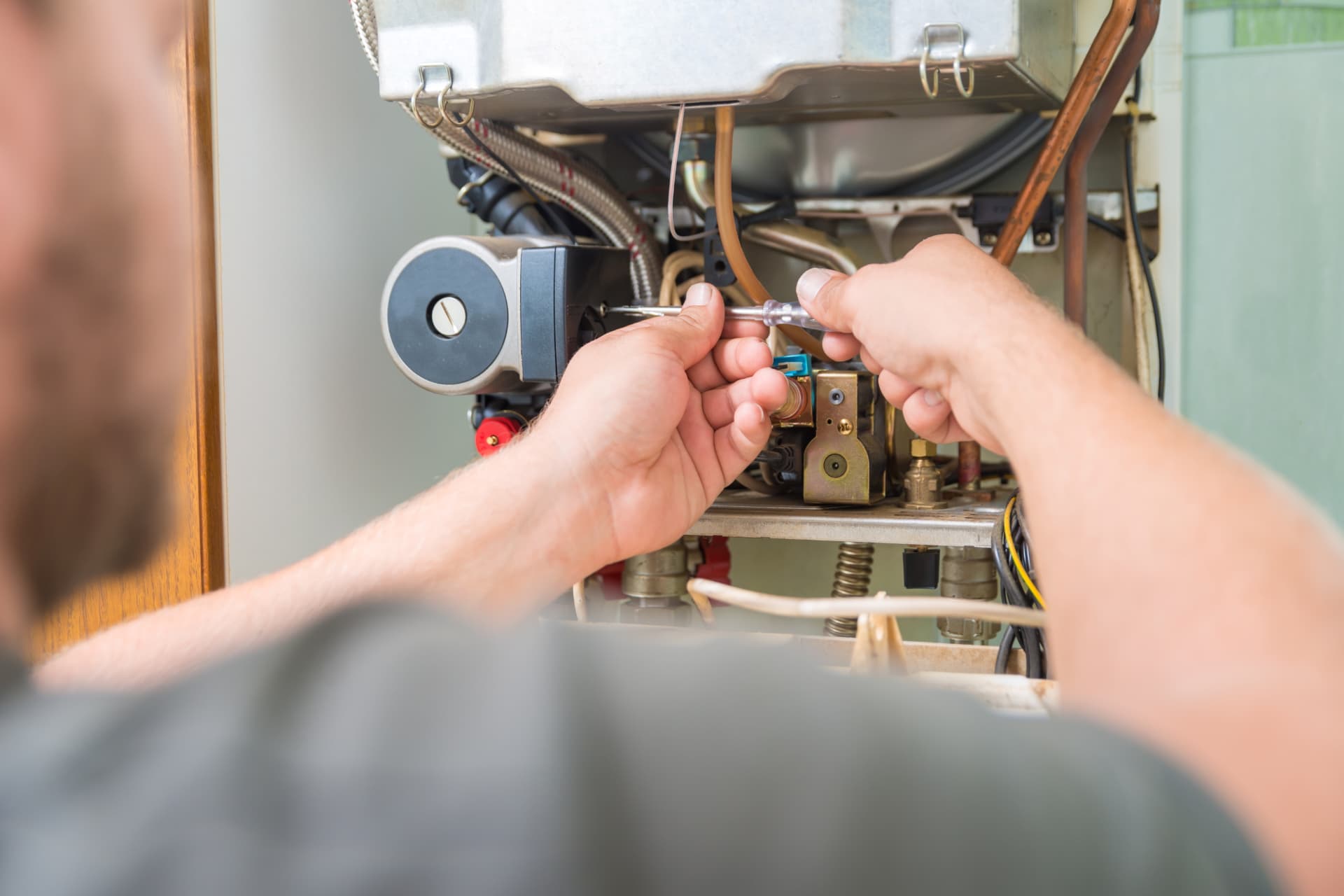 Technician adjusting an internal component during a boiler repair