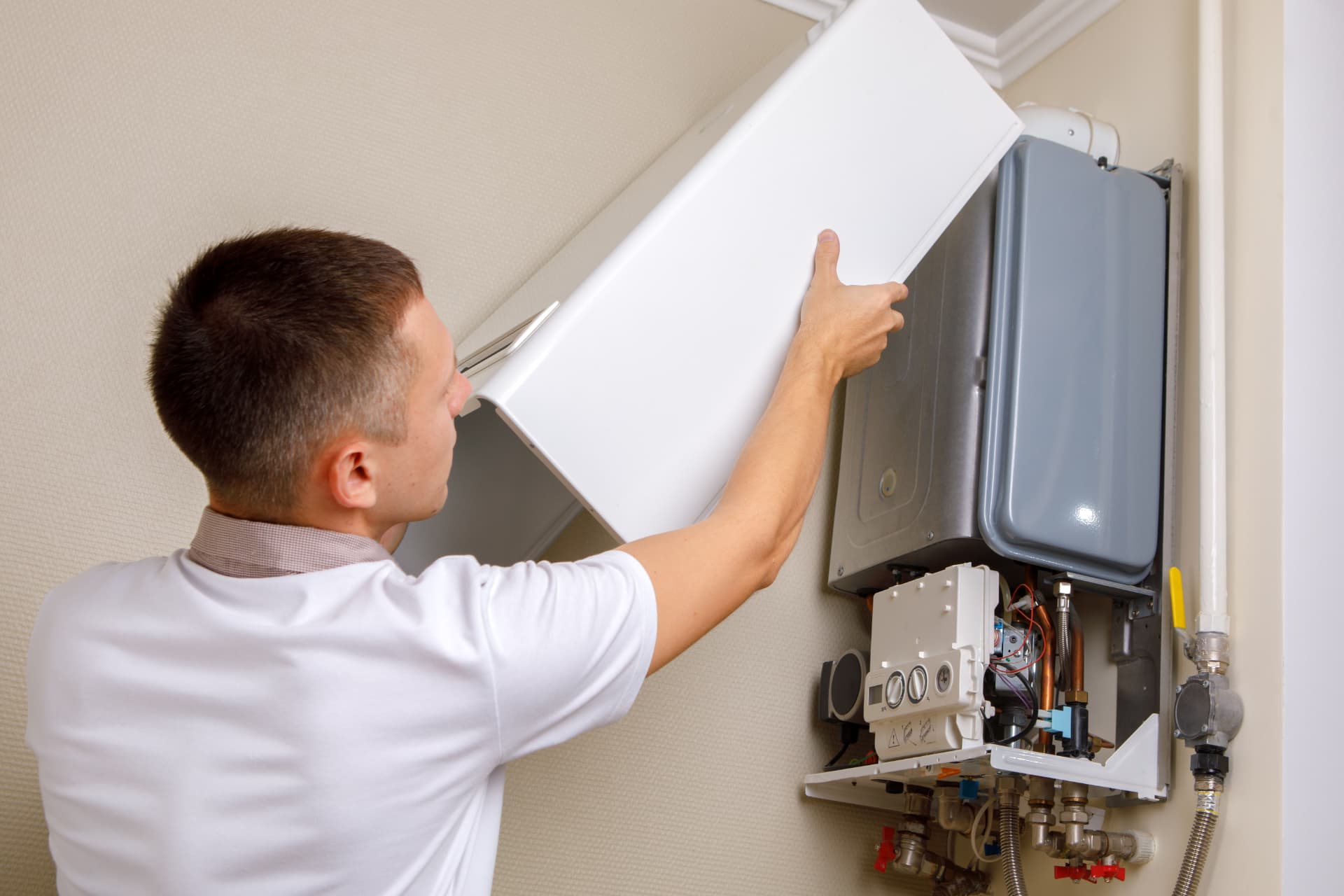 Engineer removing the casing of a wall-mounted gas boiler